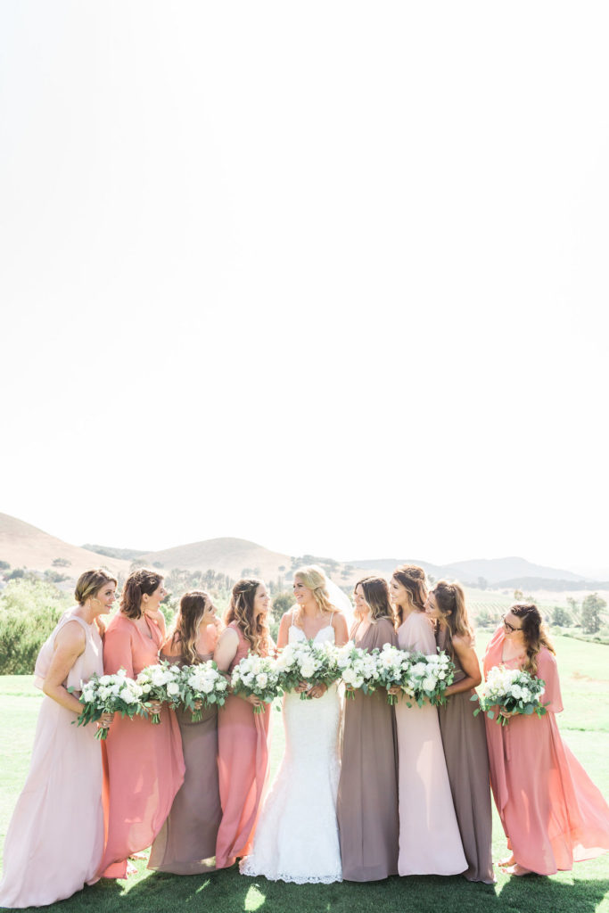 Bridesmaids in dusty rose dusty mauve and pale peach dresses by Show Me Your Mum with white flowers