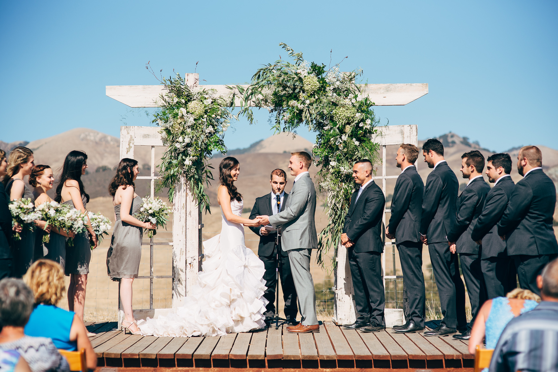 Lush ceremony flowers on rustic wood arch